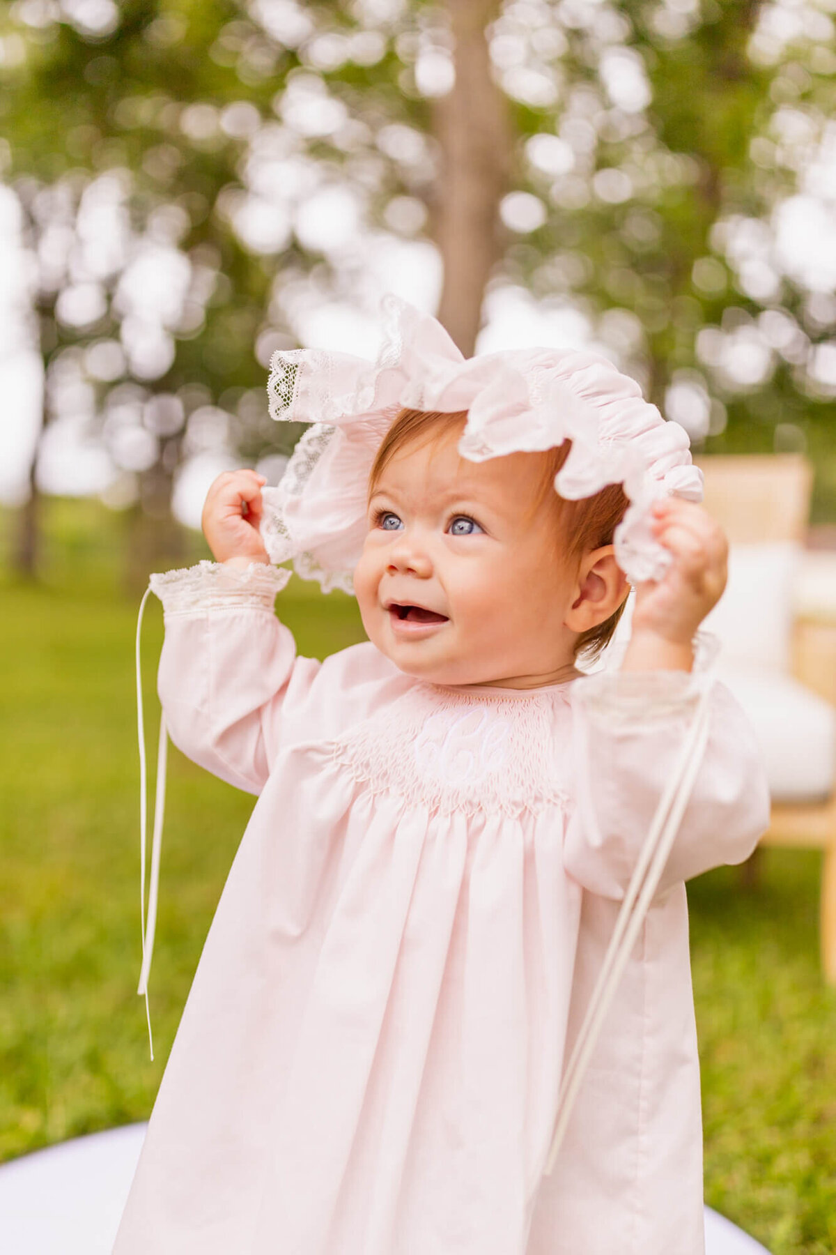 Little girl with a monogrammed pink dress and matching bonnet with lace