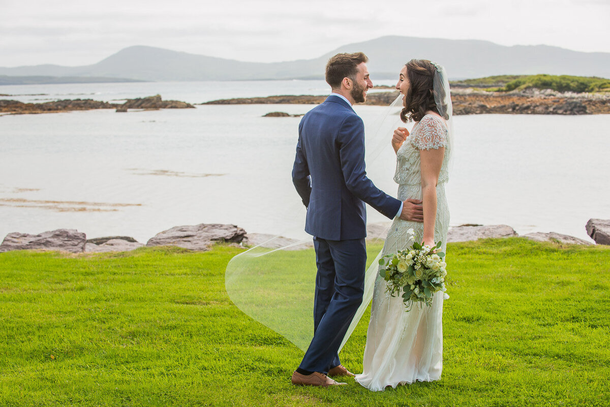 bride and groom at the first look, standing on the grass overlooking Castlecove beach in Kerry