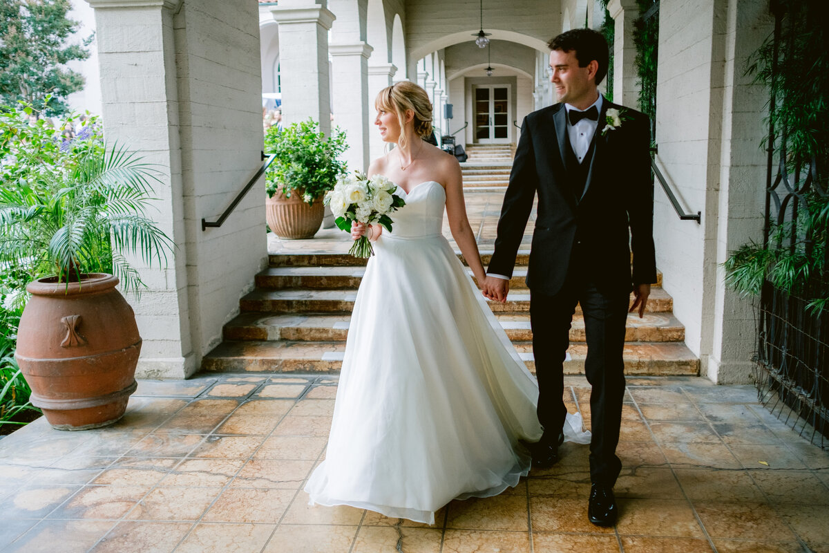 Beautiful bride and groom walk down arch covered walkway on their wedding day