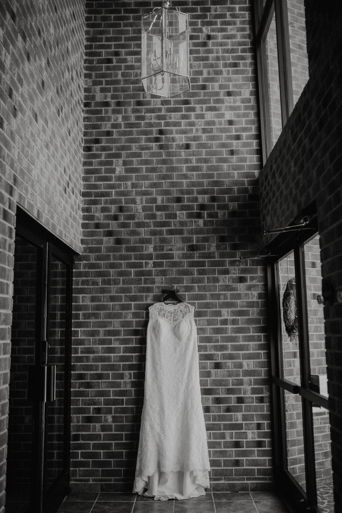 A wedding dress hangs on a brick wall