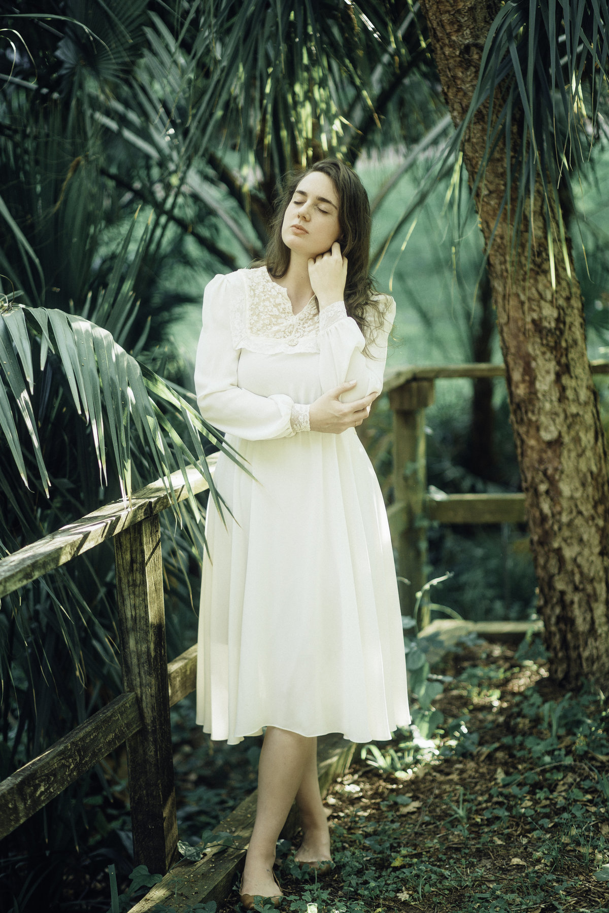 Portrait Photo Of Young Woman In White Dress Holding Her Cheek With Her Eyes Closed Los Angeles