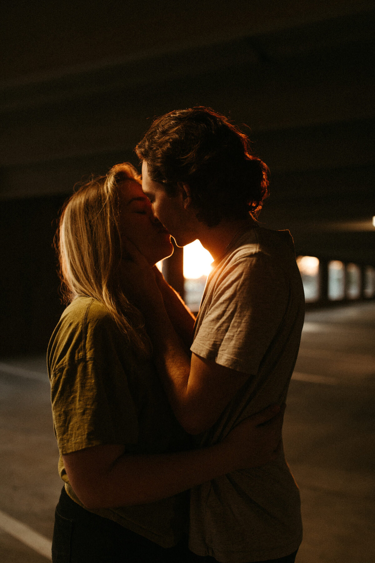 Guy pulling girl in for a kiss inside a parking garage at sunset