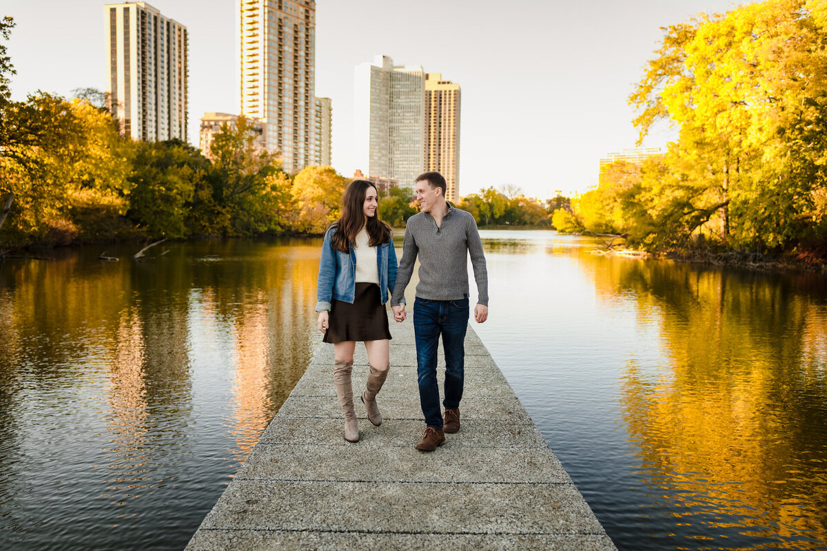 A couple walk on a dock in oover North Pond in Chicago during fall