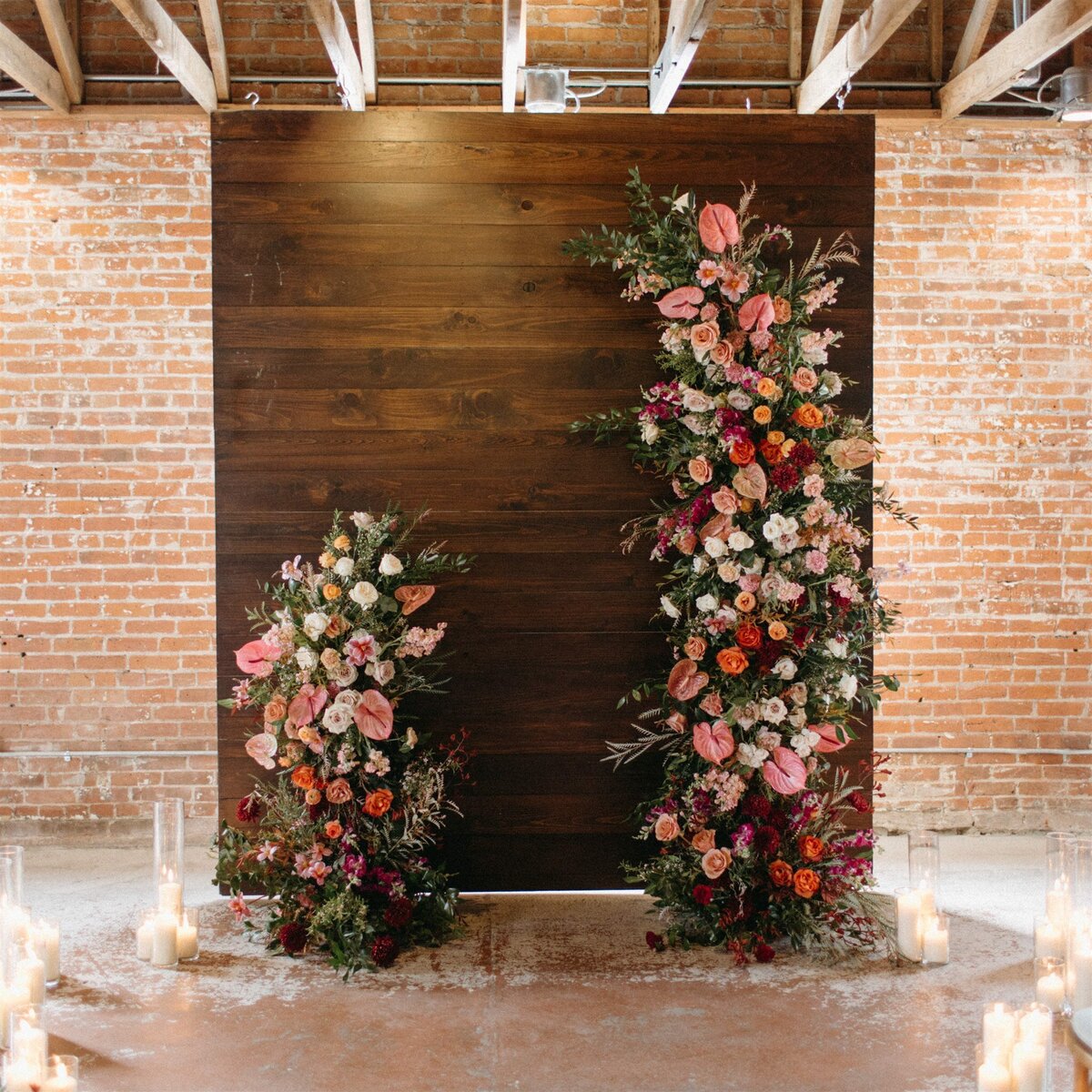 Dark walnut ceremony backdrop with colorful florals for spring wedding at The St Vrain, Longmont CO.