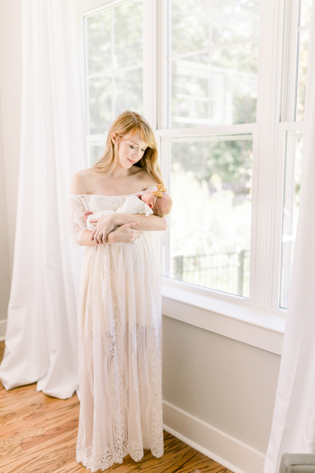 Mother holding baby next to big window