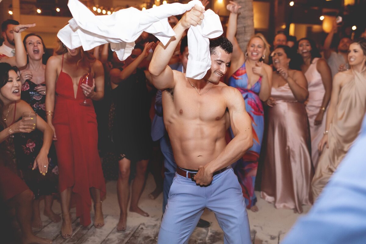 Attractive groom dancing with shirt off at  Riviera Maya wedding.