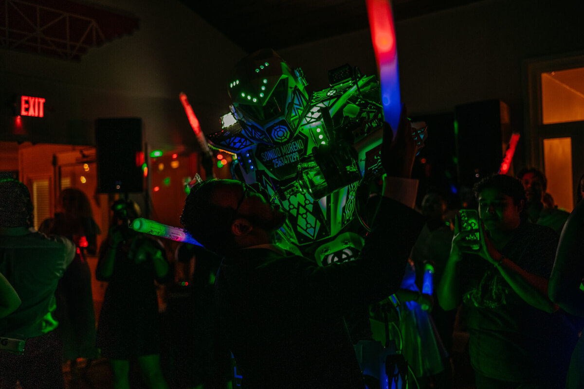 photo of a glow in the dark robot pouring alcohol into the groom's mouth