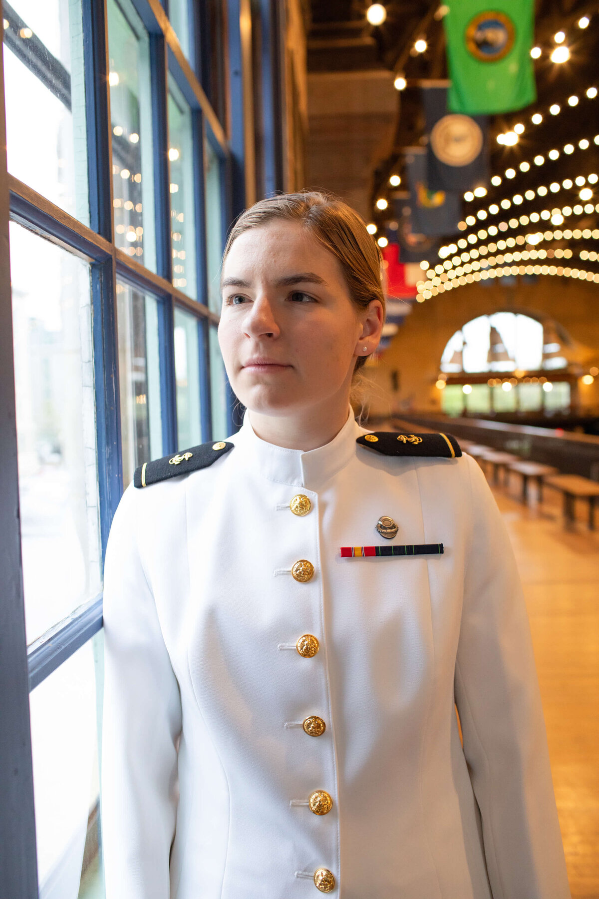 Woman Naval Academy graduate in window light from Dahlgren Hall.