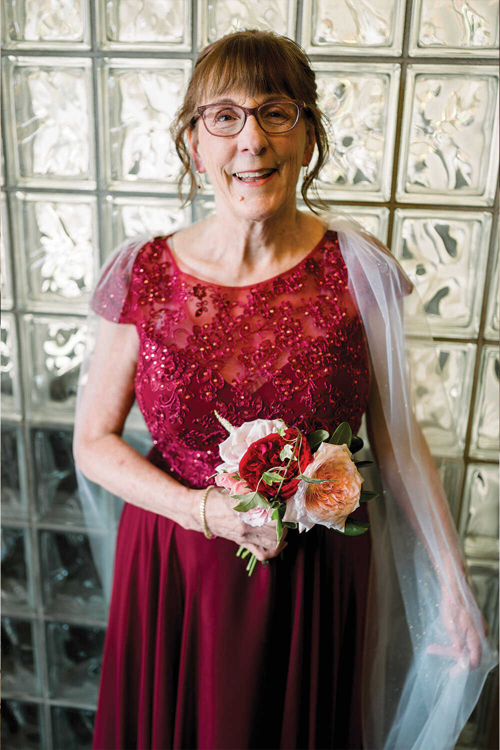Woman in a stunning red floor-length gown with intricate lace and beading, paired with a white cape, celebrating her 50th wedding anniversary at The Northern Hotel in Billings, MT.