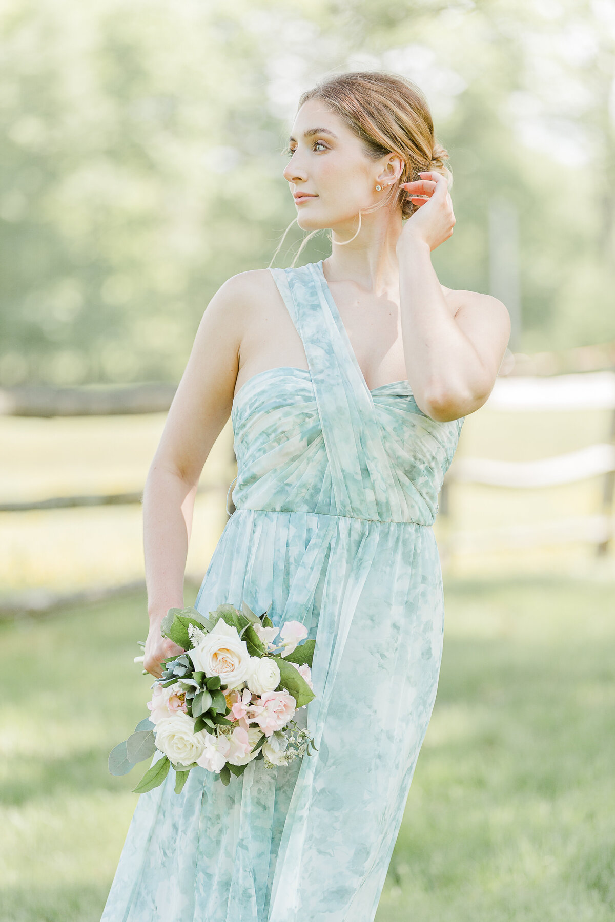 Bride in a patterned blue and cream organza dress is standing in a field for a portrait. Captured by top RI wedding photographer Lia Rose Weddings.