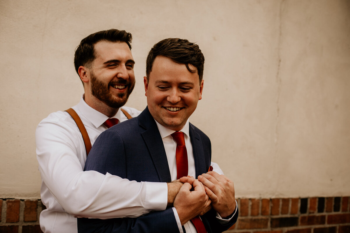 man holding his groom from behind and laughing