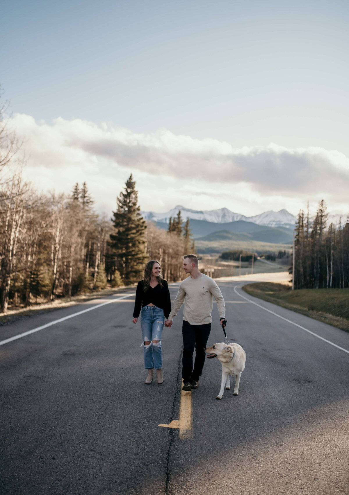 man and woman walk on road with their dog