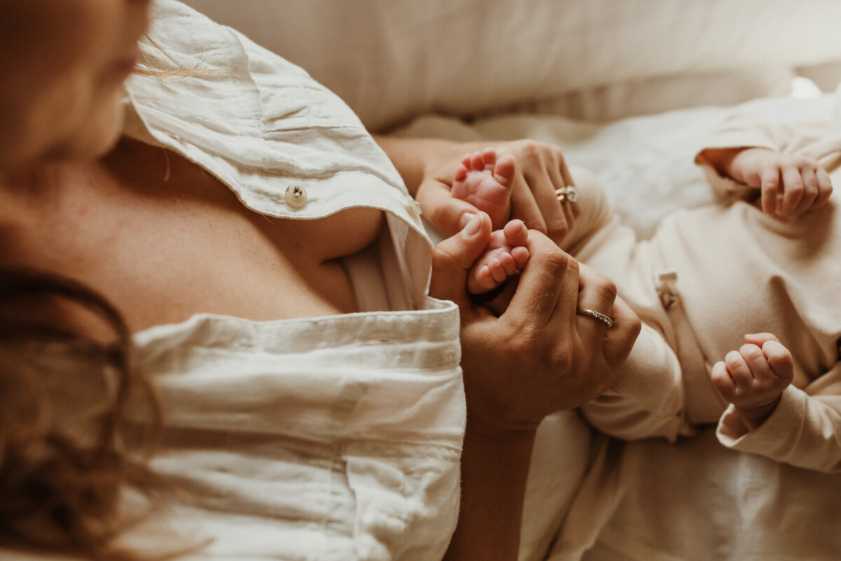 Lifestyle newborn photo of mom holding baby toes.