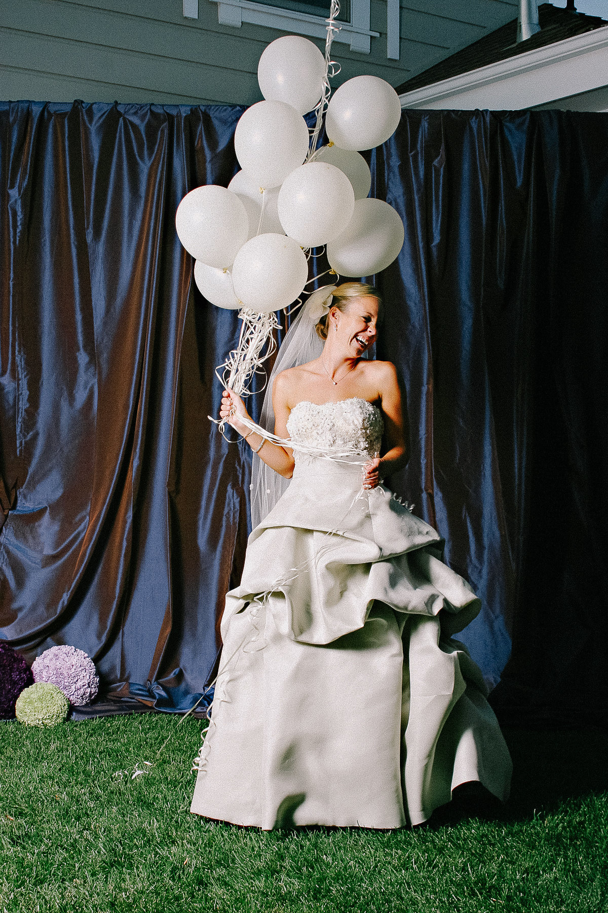 A bride poses with white balloons for her wedding in Napa.