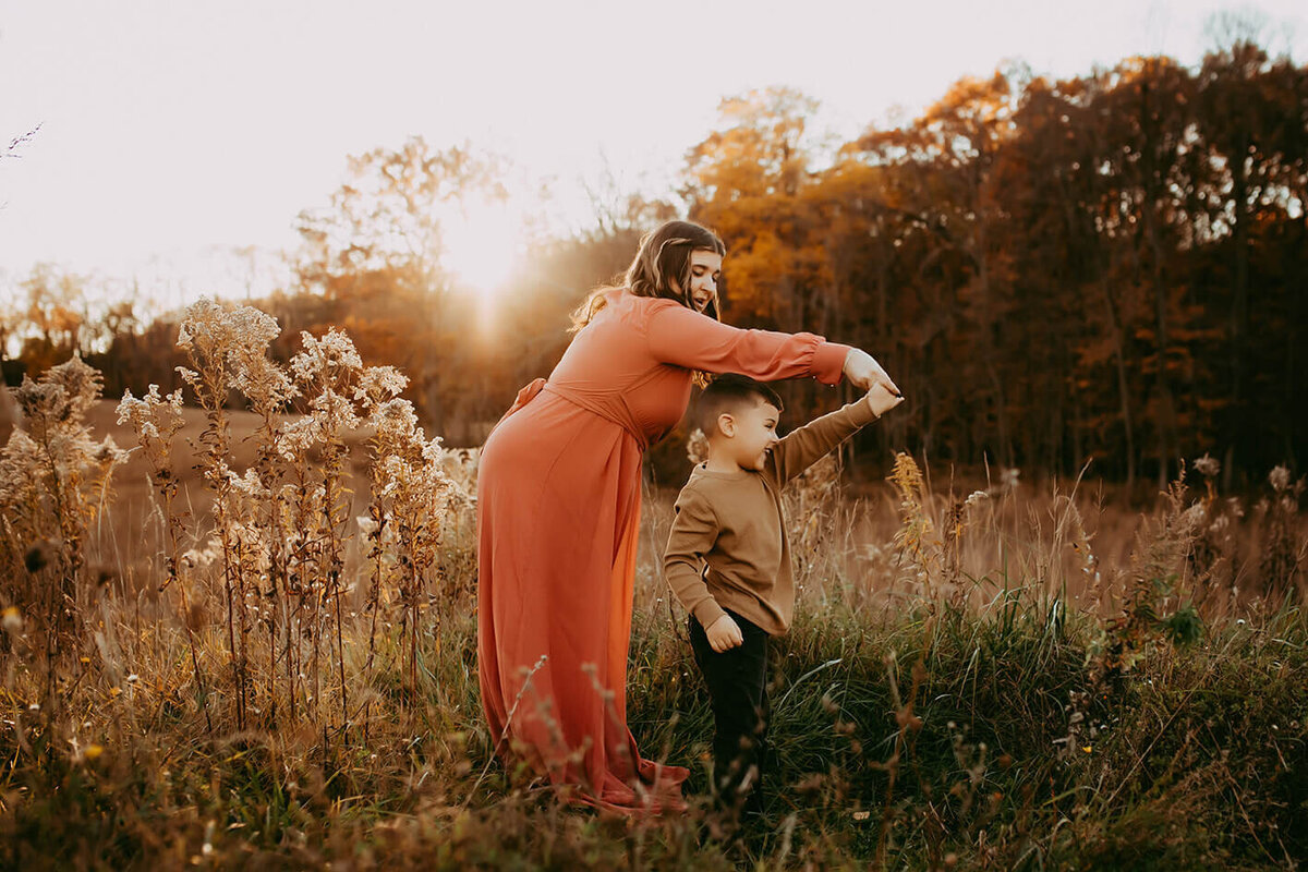 a mother and son dancing in a field at sunset in rochester, ny