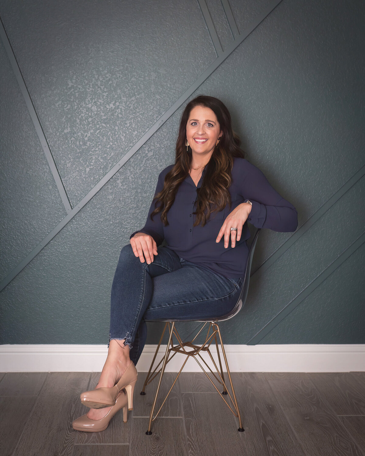 woman sitting in a clear chair with gold legs, looking happy and confident posing for an on-location branding headshot