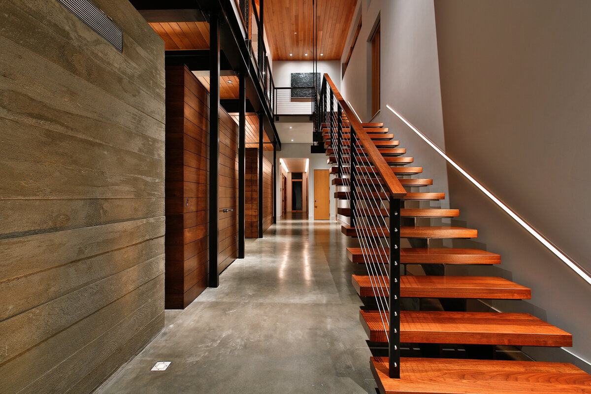 Concrete floor hallway with wooden staircase and wood features