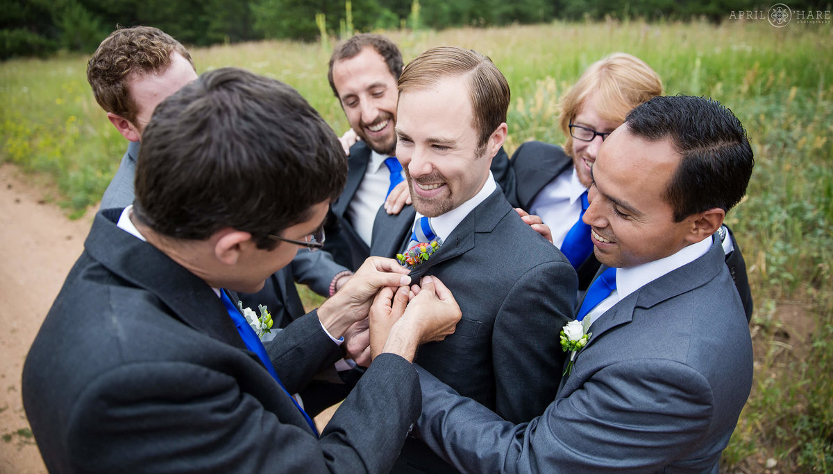 Groom surrounded by best friends gets help with his boutonniere at Wedgewood Mountain View Ranch in Colorado