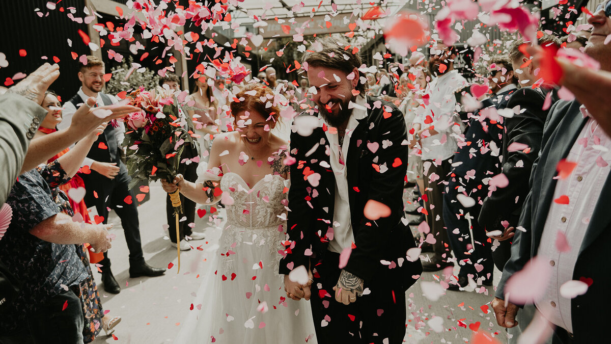 A bride and groom walk through a tunnel of confetti thrown by their guests at The Shack Revolution. 