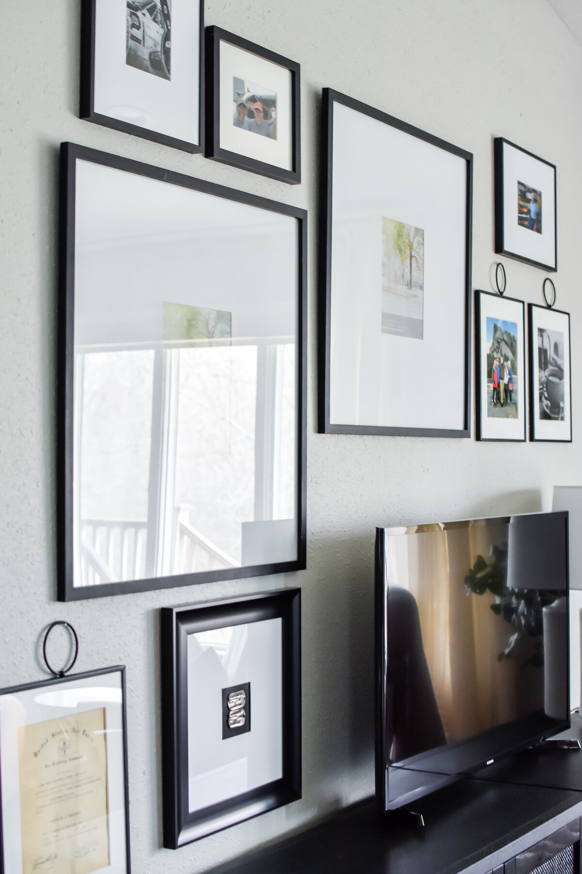 Several photos in black frames hung on the wall behind a TV console