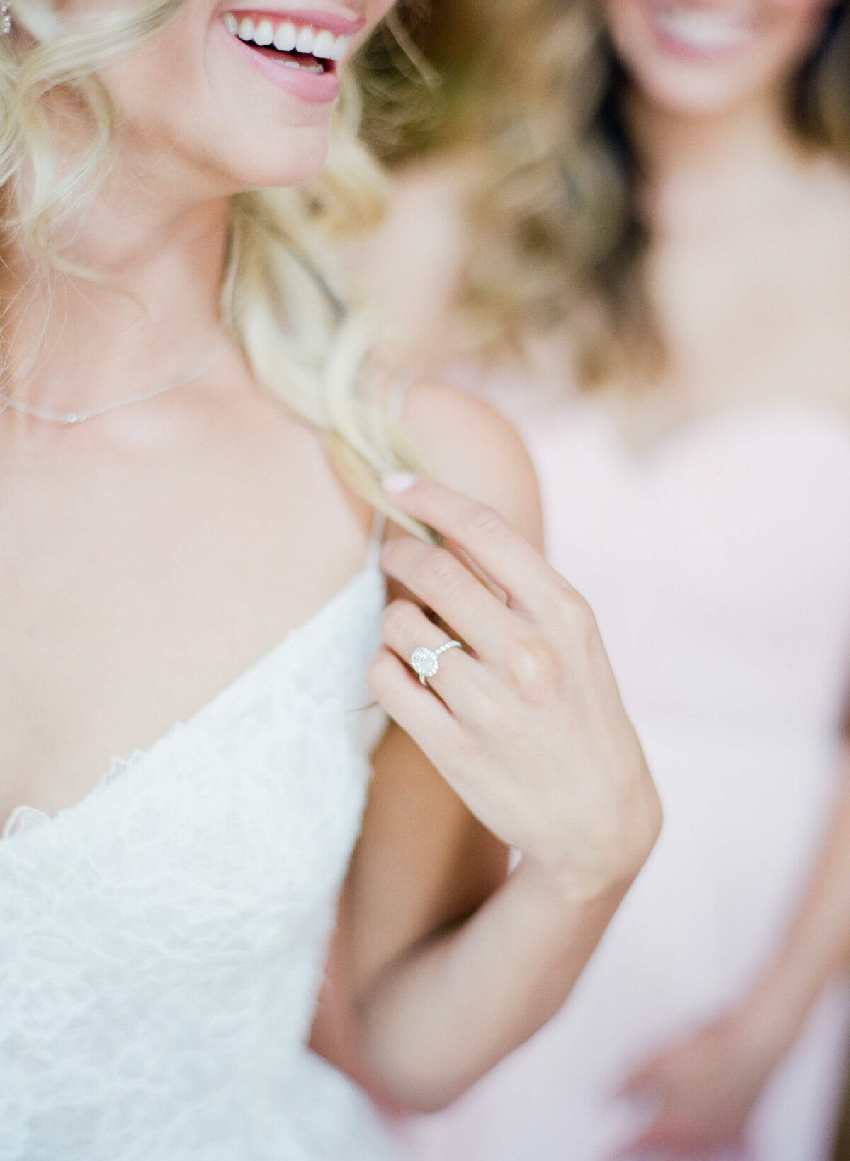 Bride displays her beautiful diamond ring while wearing a sleeveless wedding gown.
