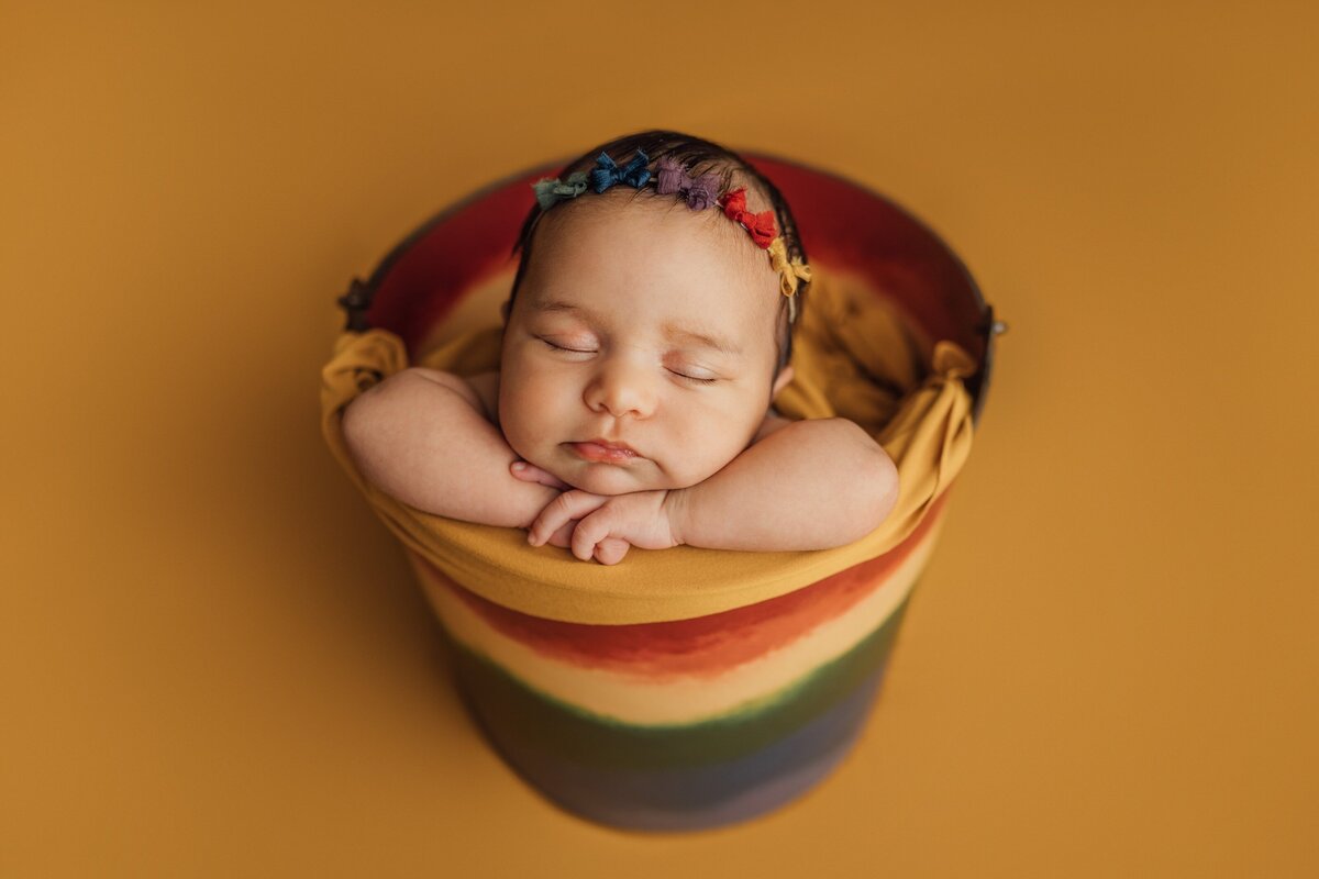 newborn baby posed in rainbow bucket prop in Tampa, FL