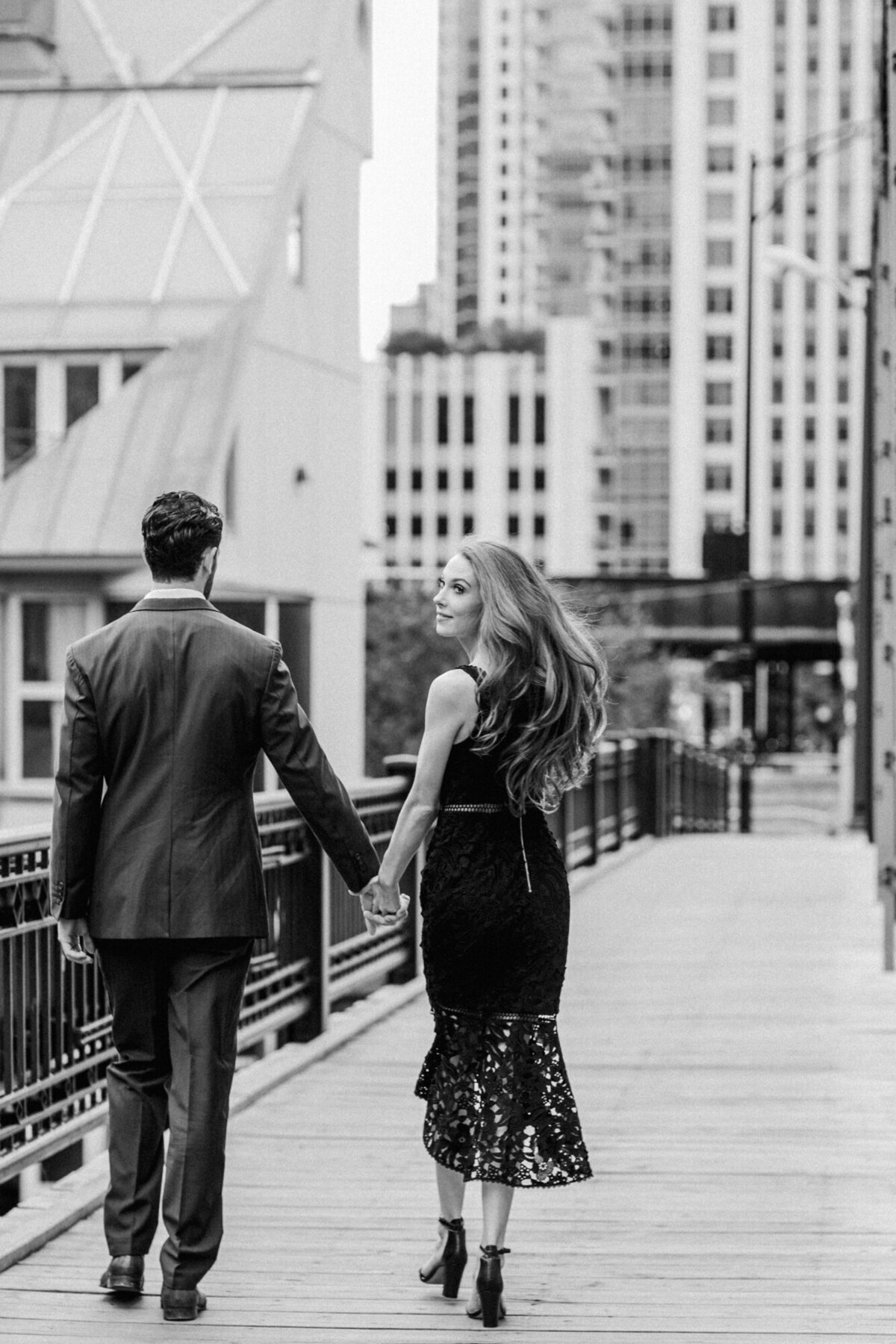 A couple walks across the Kinzie Street Bridge in Chicago for an engagement photo
