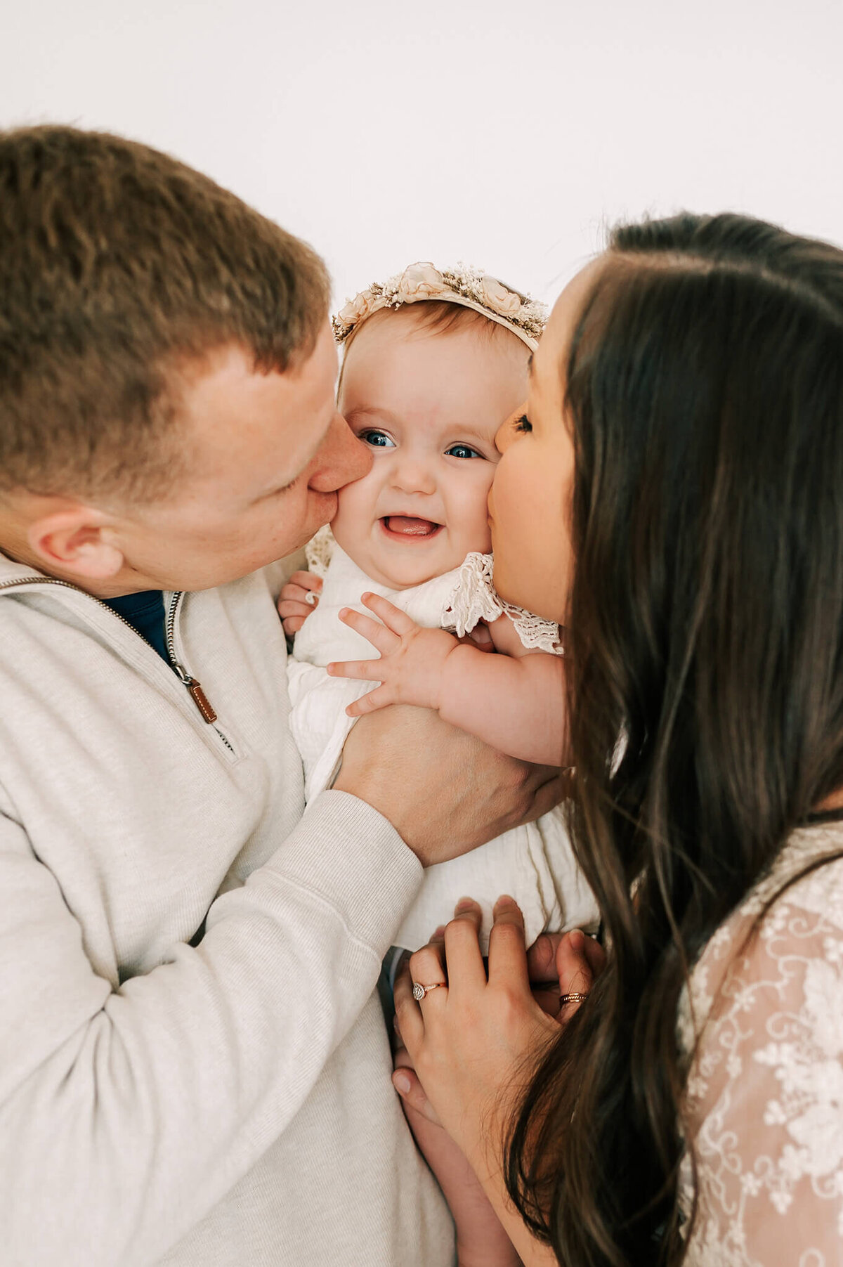parents kissing baby cheeks in family photography studio in Springfield MO