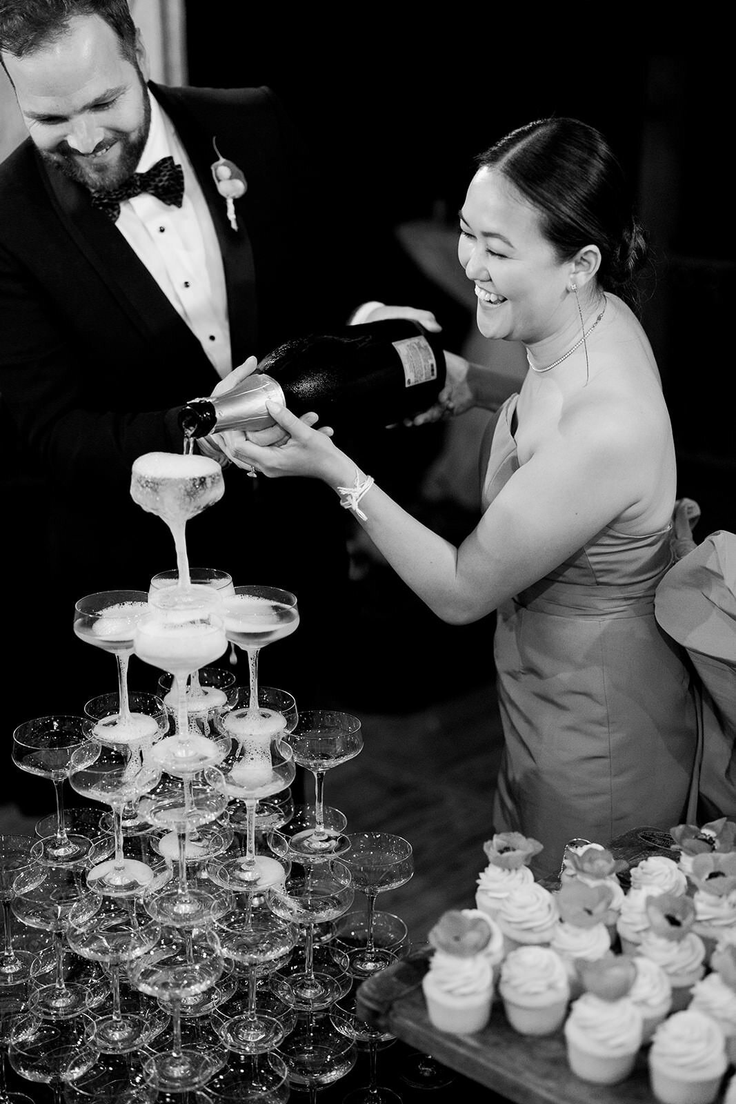 Bride and groom pour champagne over champagne glass tower