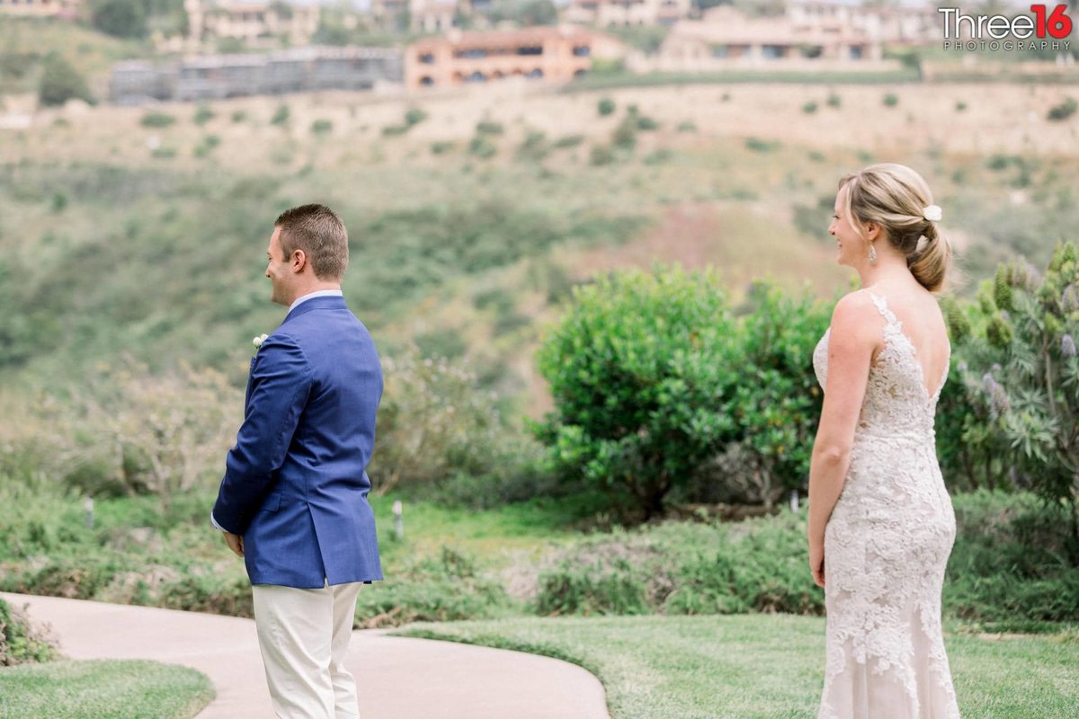 Bride walks up behind Groom during first look photo session