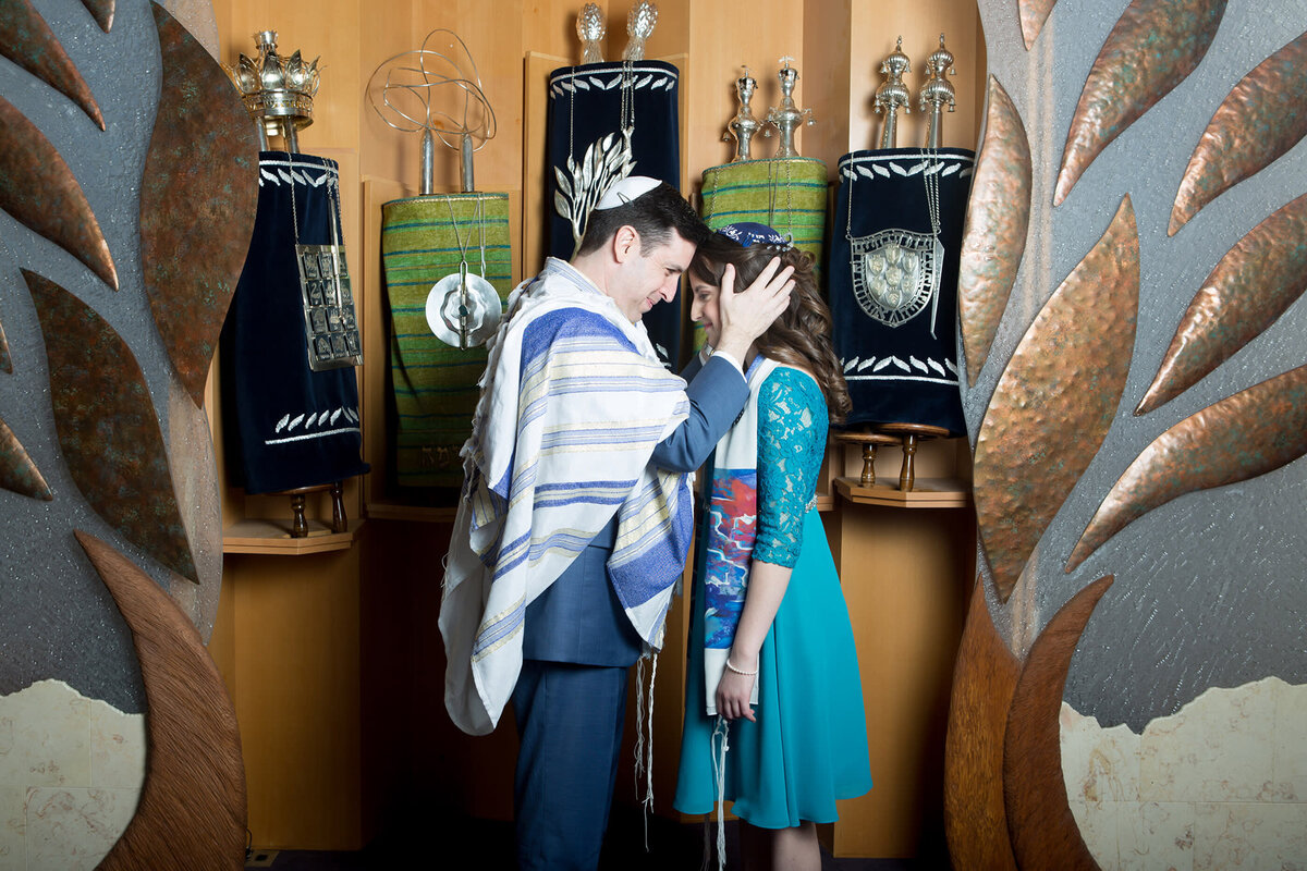 rabbi in a prayer shawl bless a teenage girl in an aqua dress in front of Torah scrolls Reform Temple of Rockland bat mitzvah photographer Nyack bar mitzvah photographer