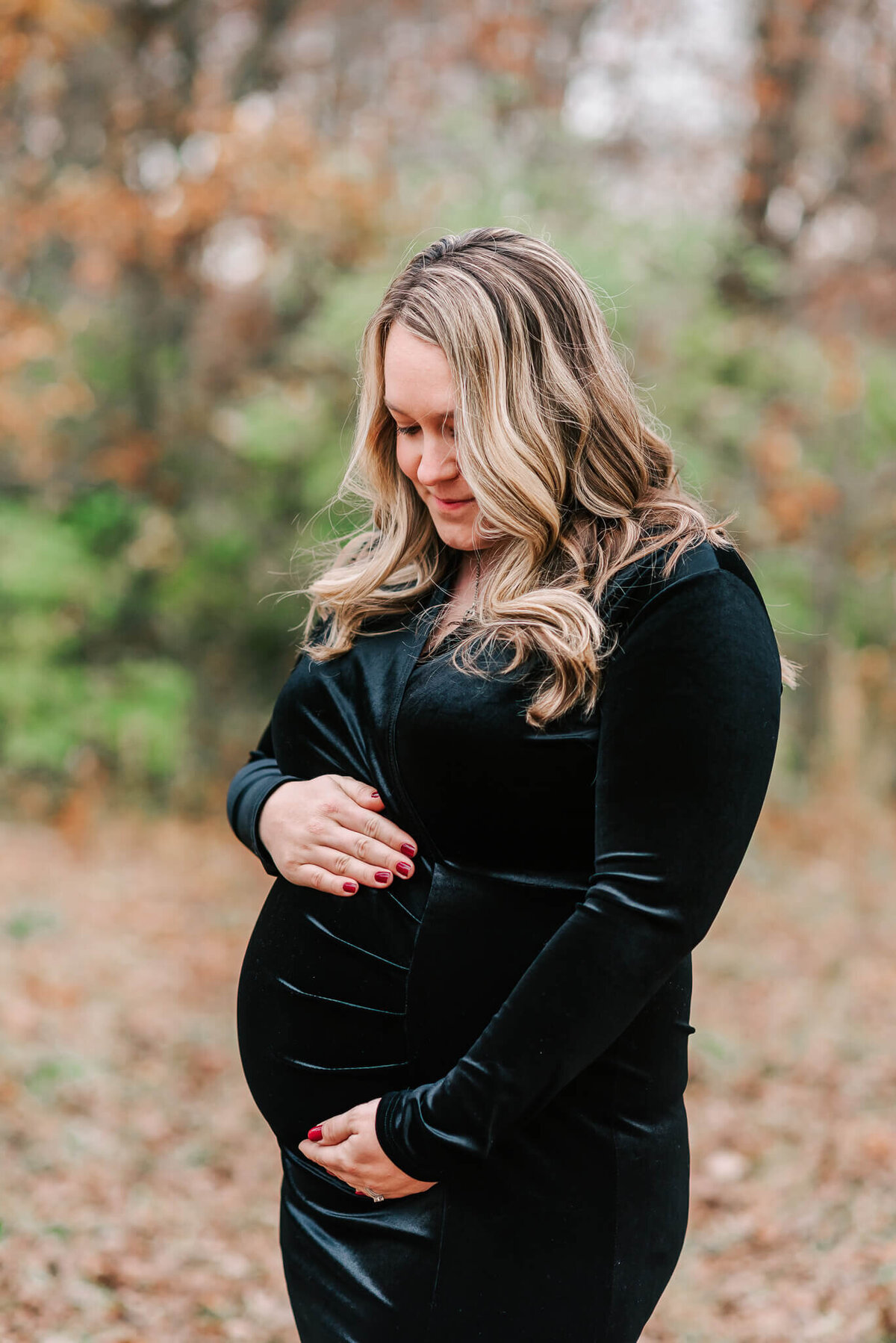 A stunning mother wearing black velvet, holding her baby bump during her maternity session in Northern Virginia