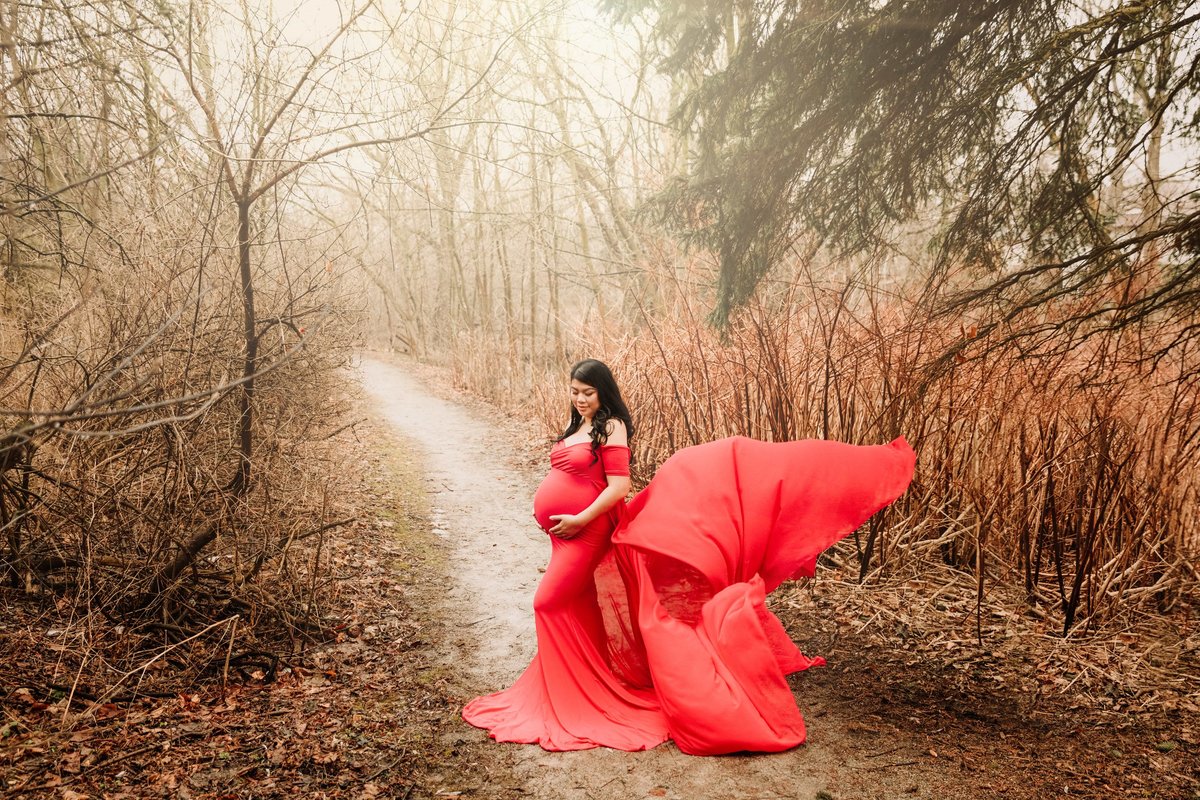 Mom in red maternity gown in forest