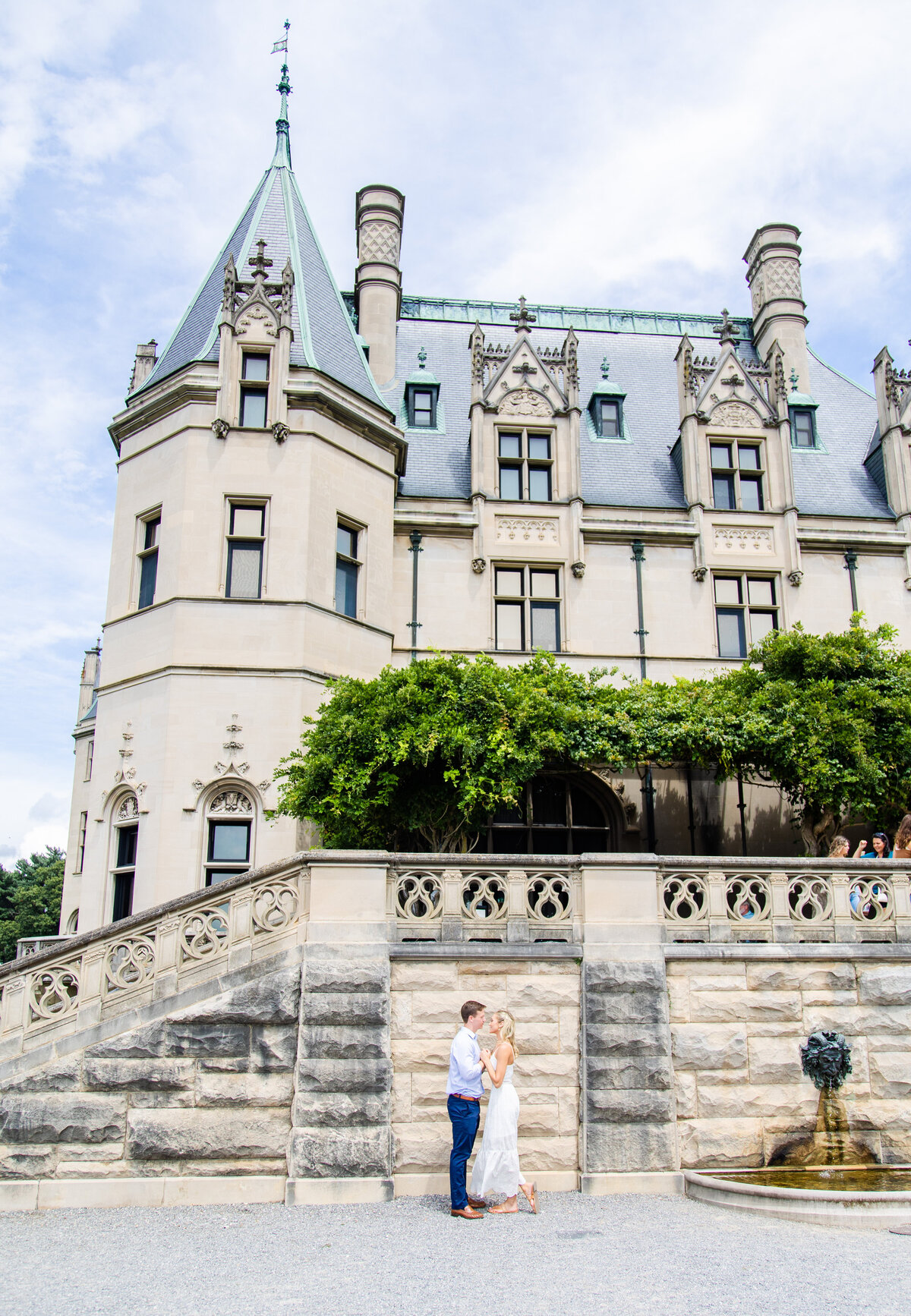 couple facing each other with Biltmore Estate castle in the background