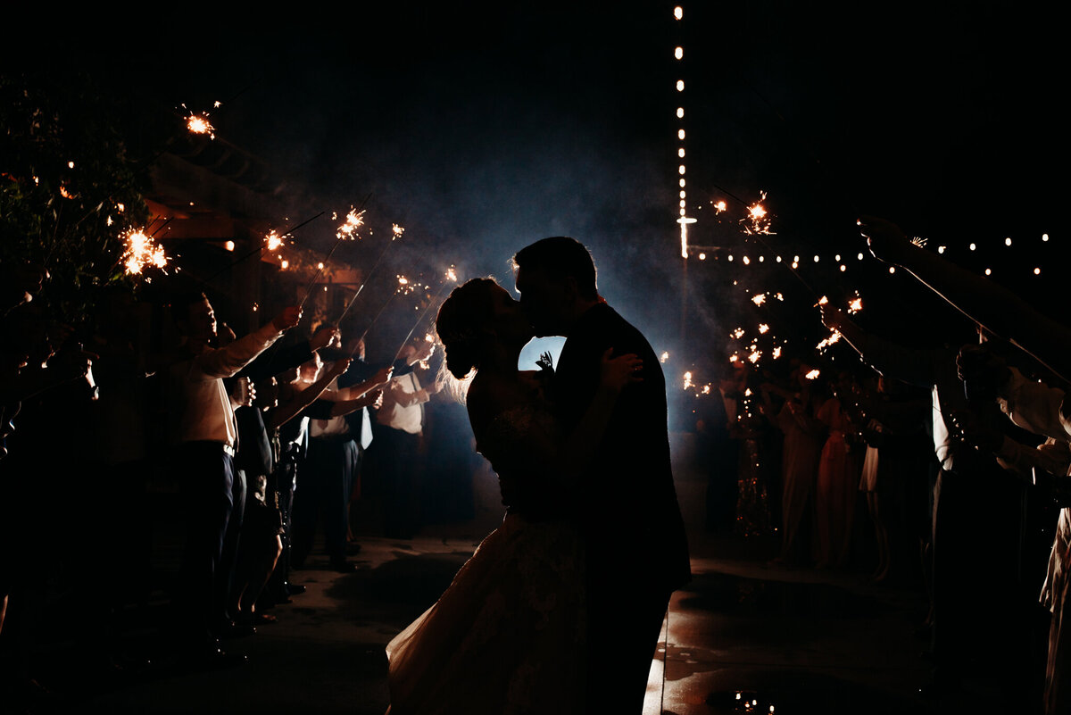 photo of a silhouette of two people kissing in between a tunnel of sparklers