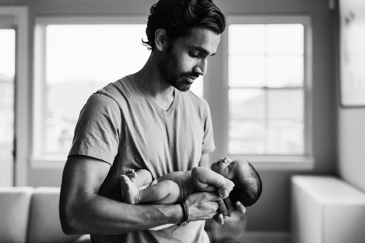 Father holding infant in-home in black and white