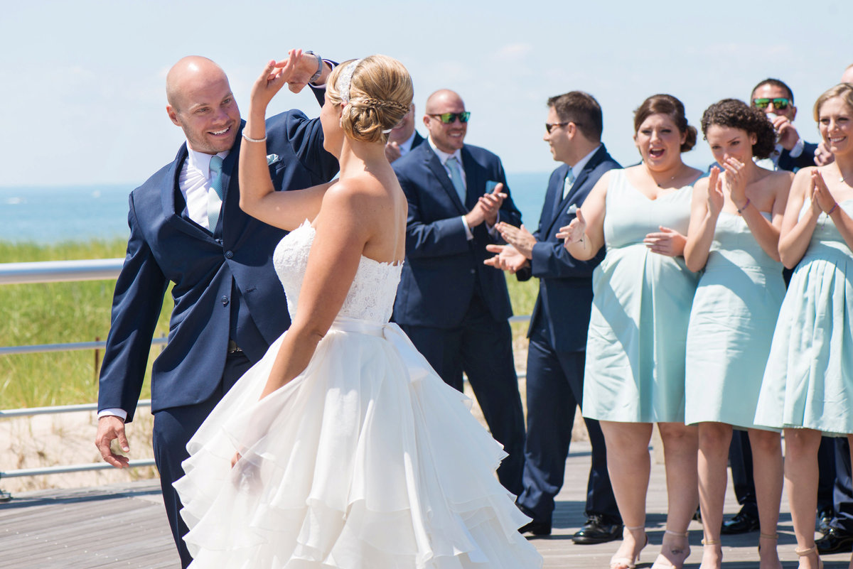 photo of groom twirling his bride on the boardwalk from wedding reception at Pavilion at Sunken Meadow