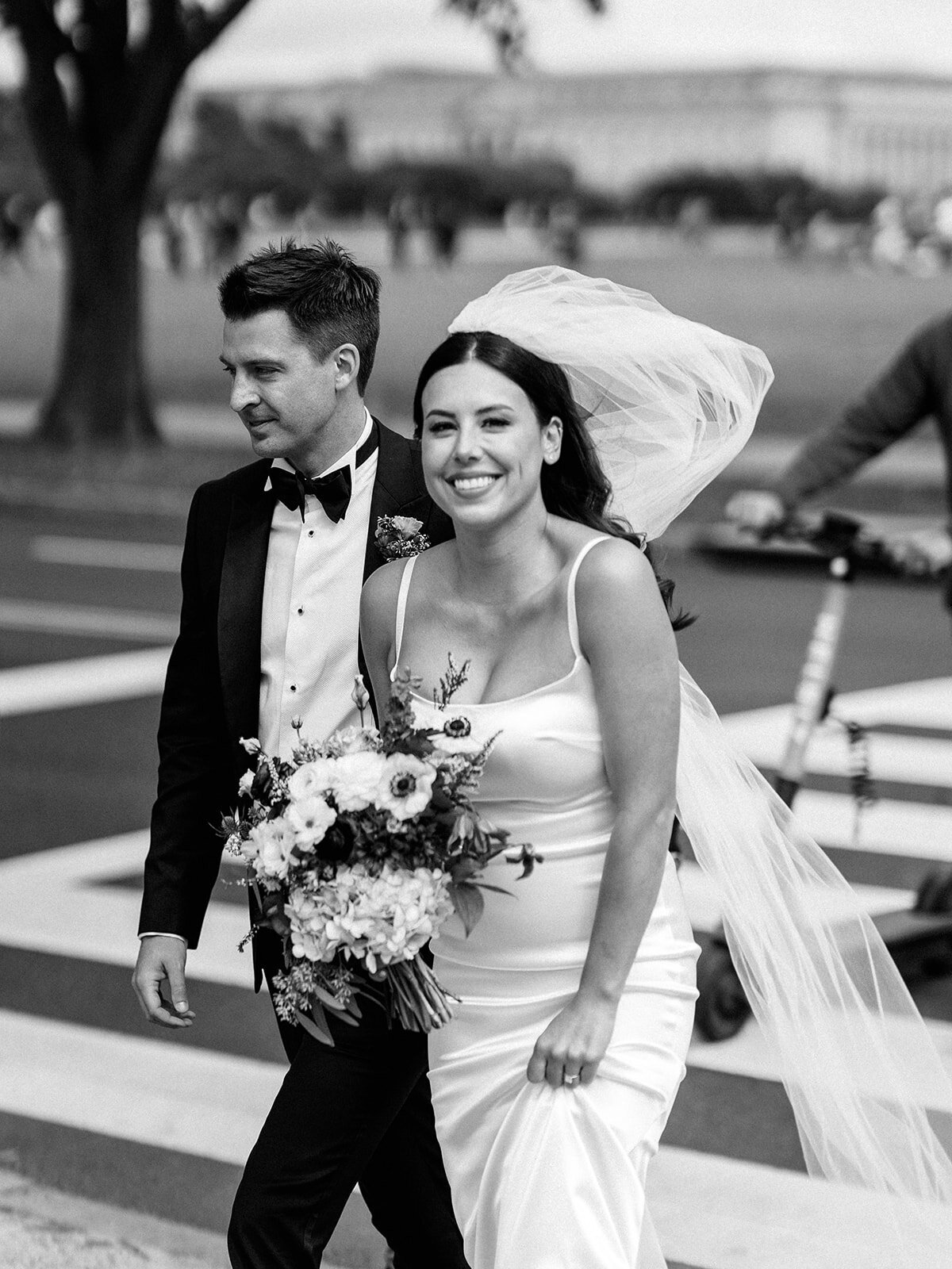 A black and white photo of bride and groom walking through DC