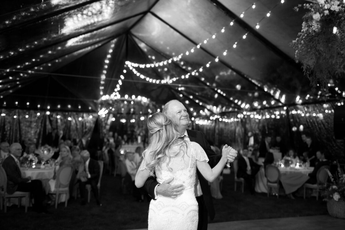 Bride dances in a dimly illuminated hall at the afterparty with her guests in attendance.