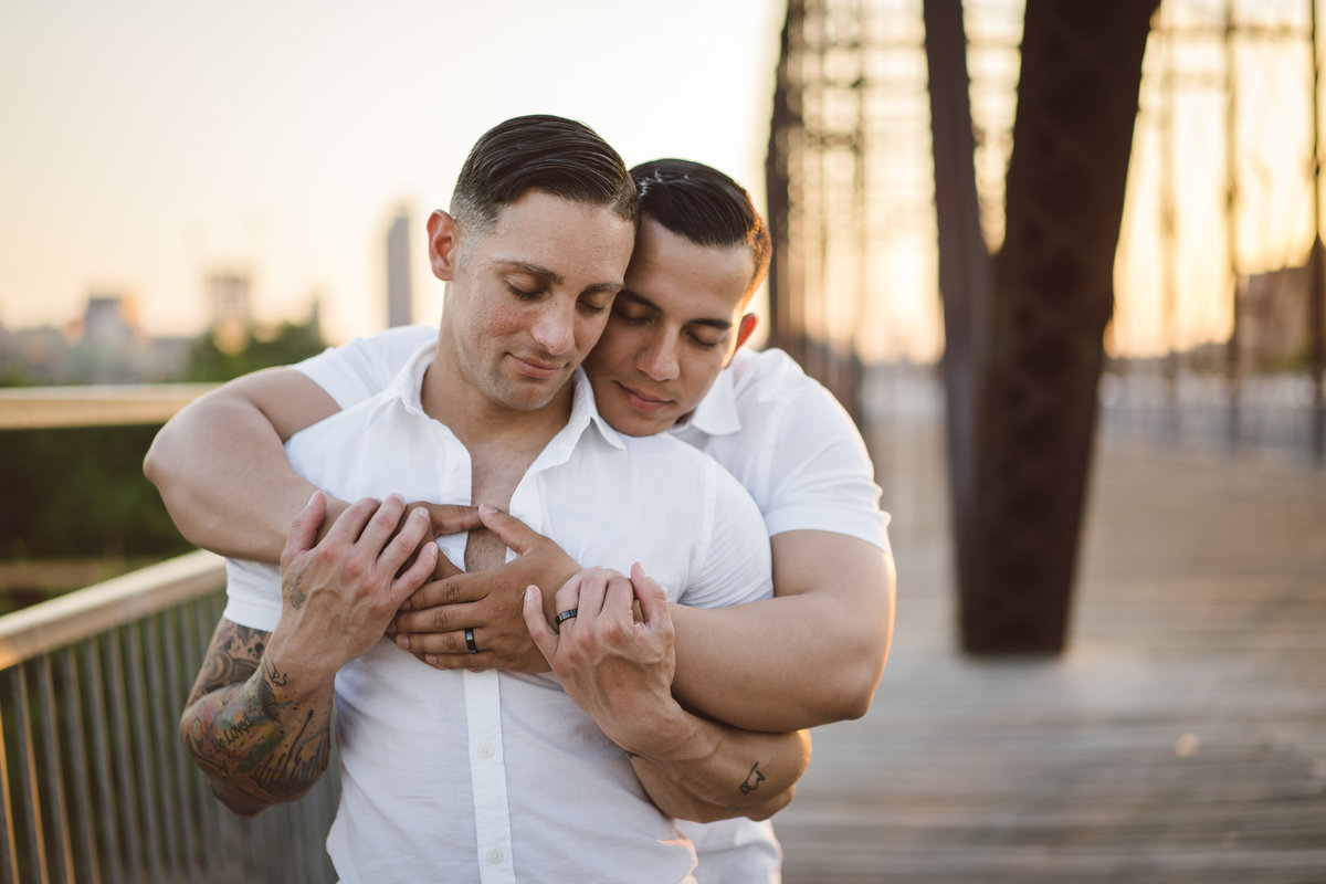 Engaged couple, two men holding each other while standing on Hays Street Bridge. Same sex engagement session.