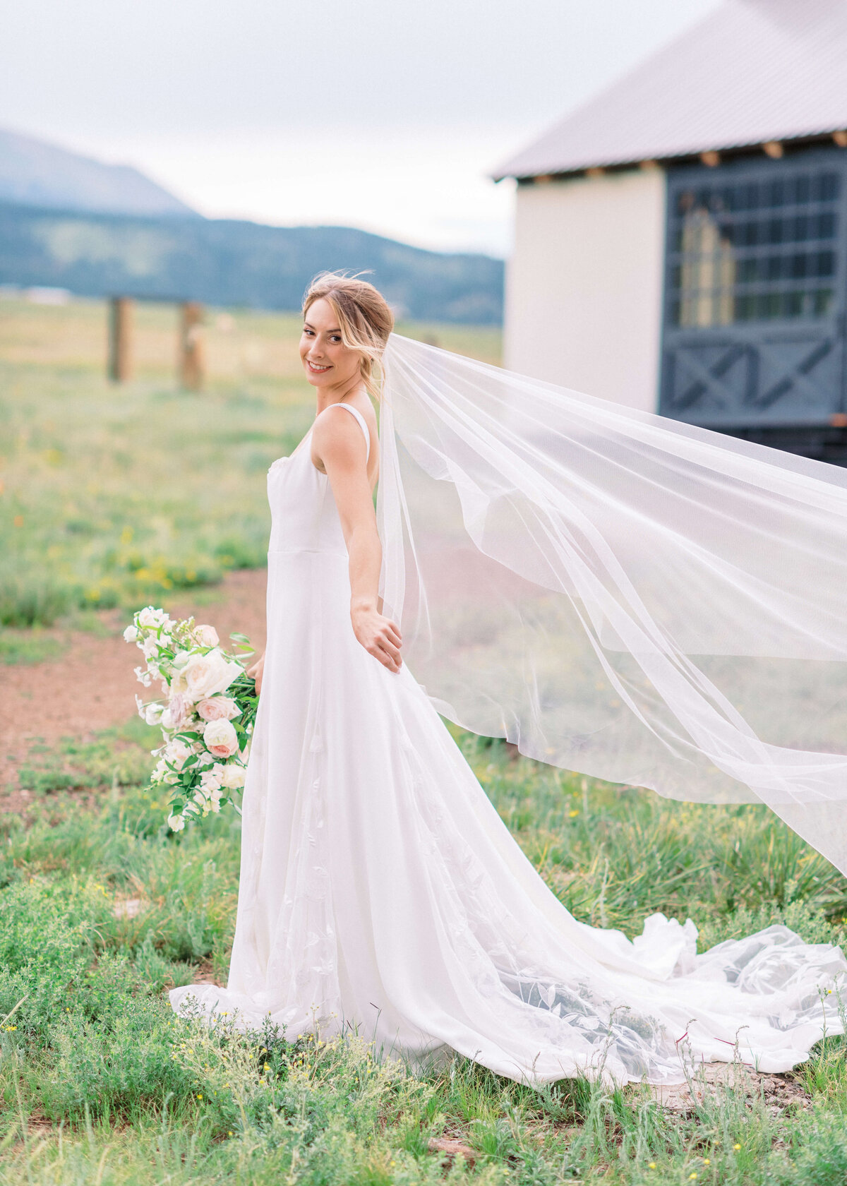 During a fun and whimsical moment, the bride waves her veil in the wind