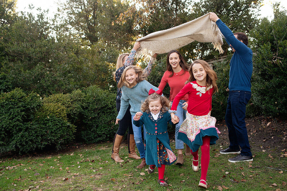 Family session of children running underneath a blanket