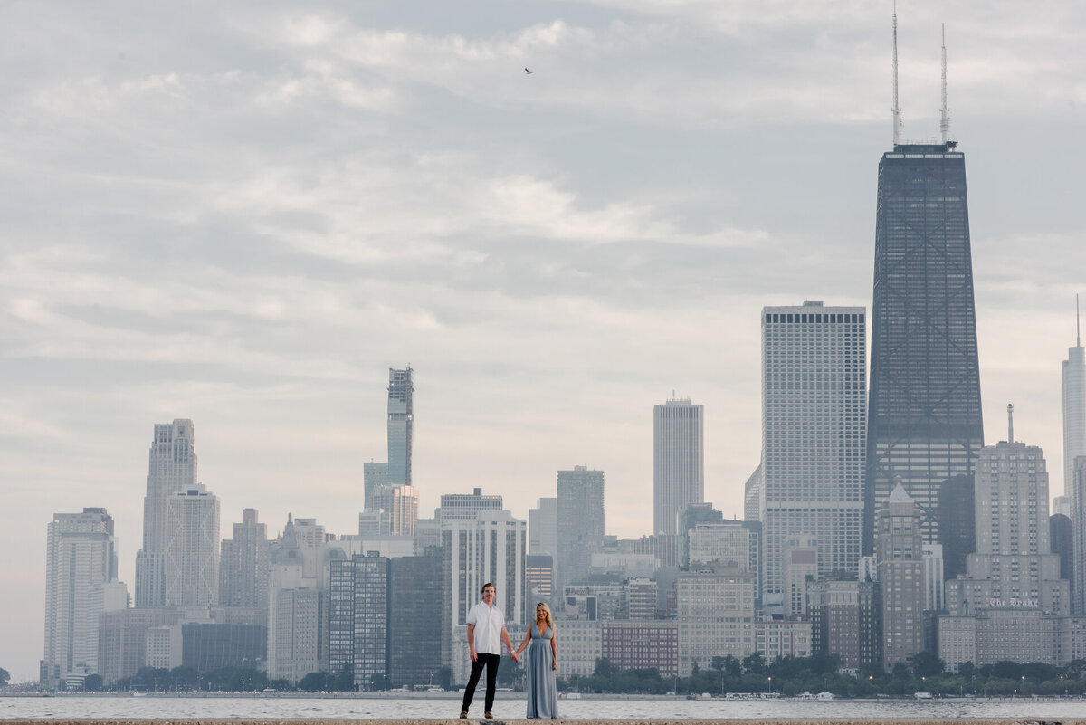 A couple stand in front of  the Chicago skyline at North Avenue Beach