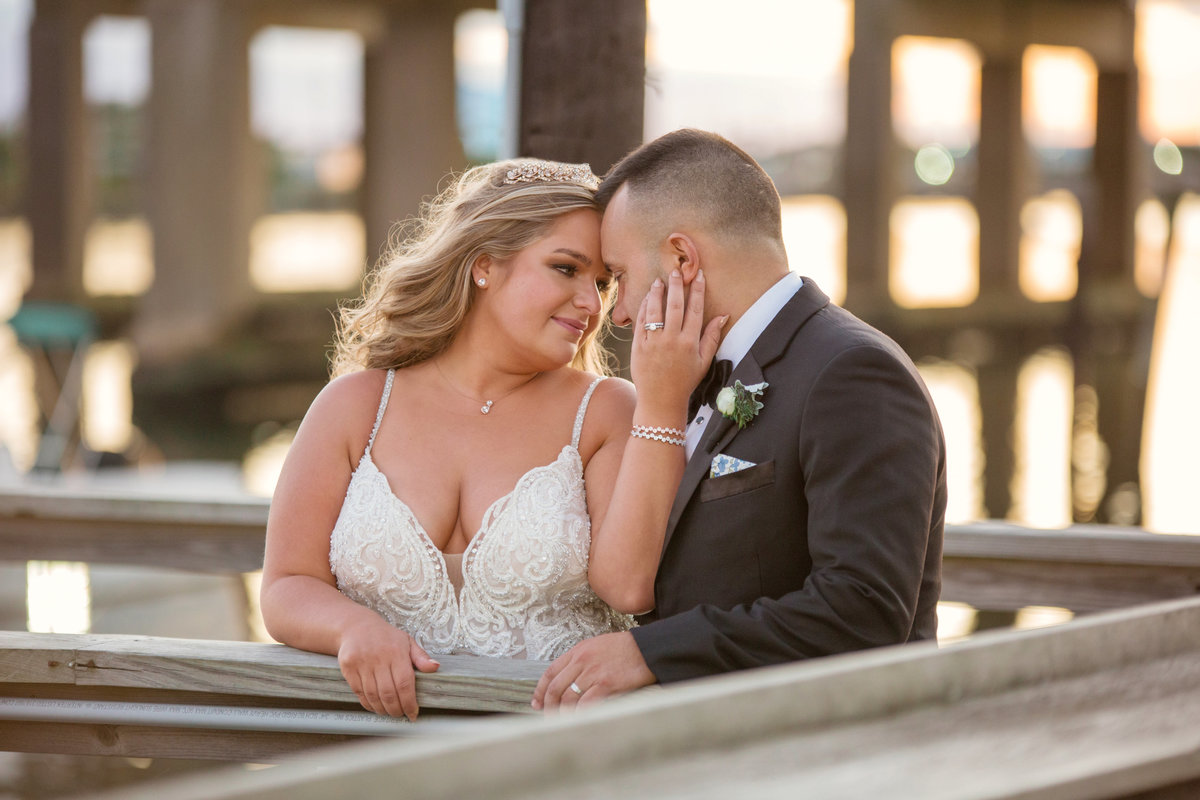 bride holding grooms face on boardwalk of Bridgeview Yacht Club