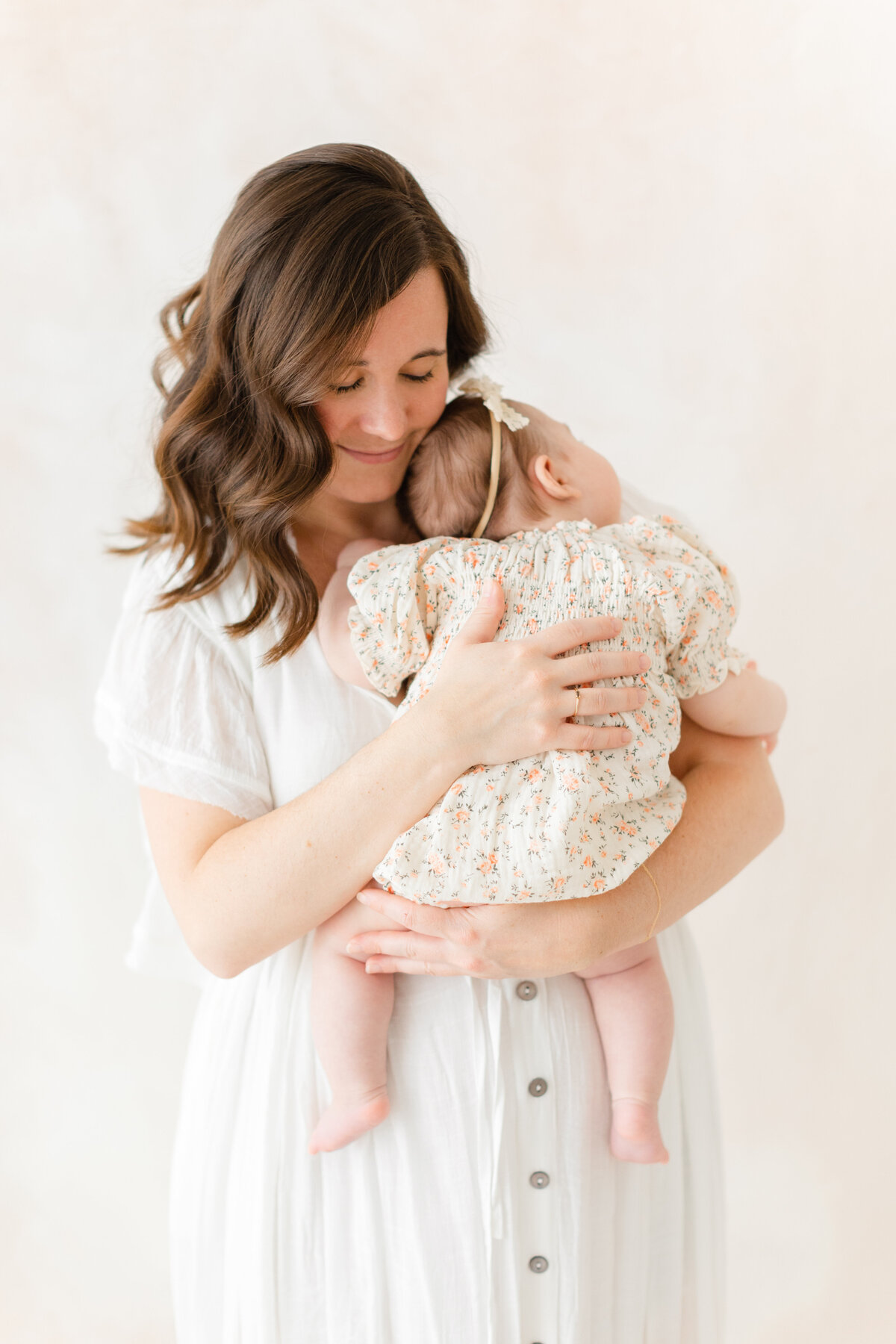 A Baby Photography photo in Northern Virginia of a mother holding her 6 month old baby girl in front of a hand-painted canvas backdrop