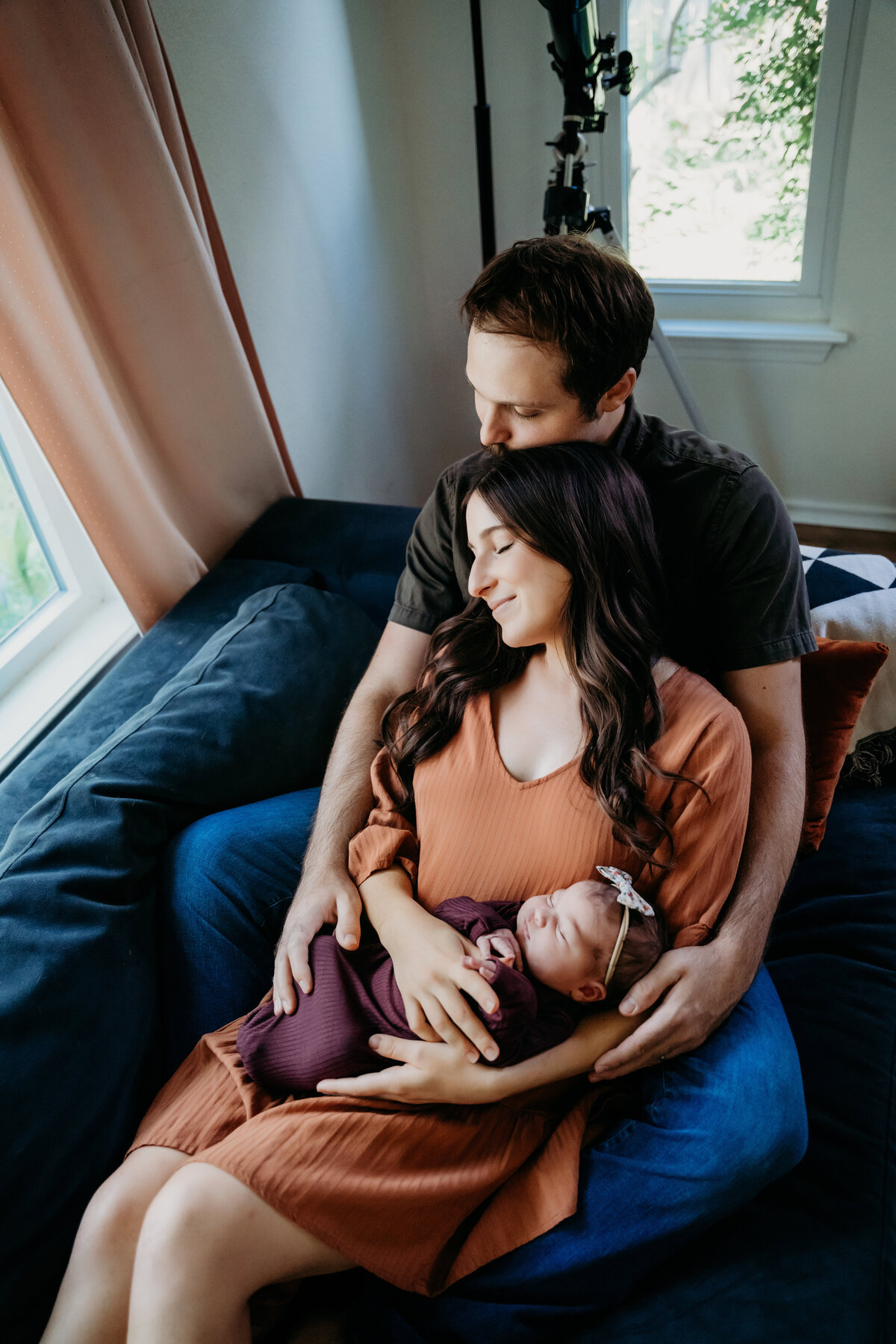 Newborn Photographer, a woman reclines into her husband as she holds baby