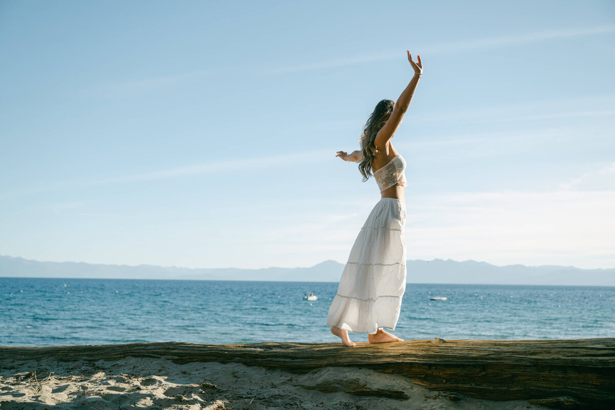 lake tahoe senior girl facing the lake hands in the air.