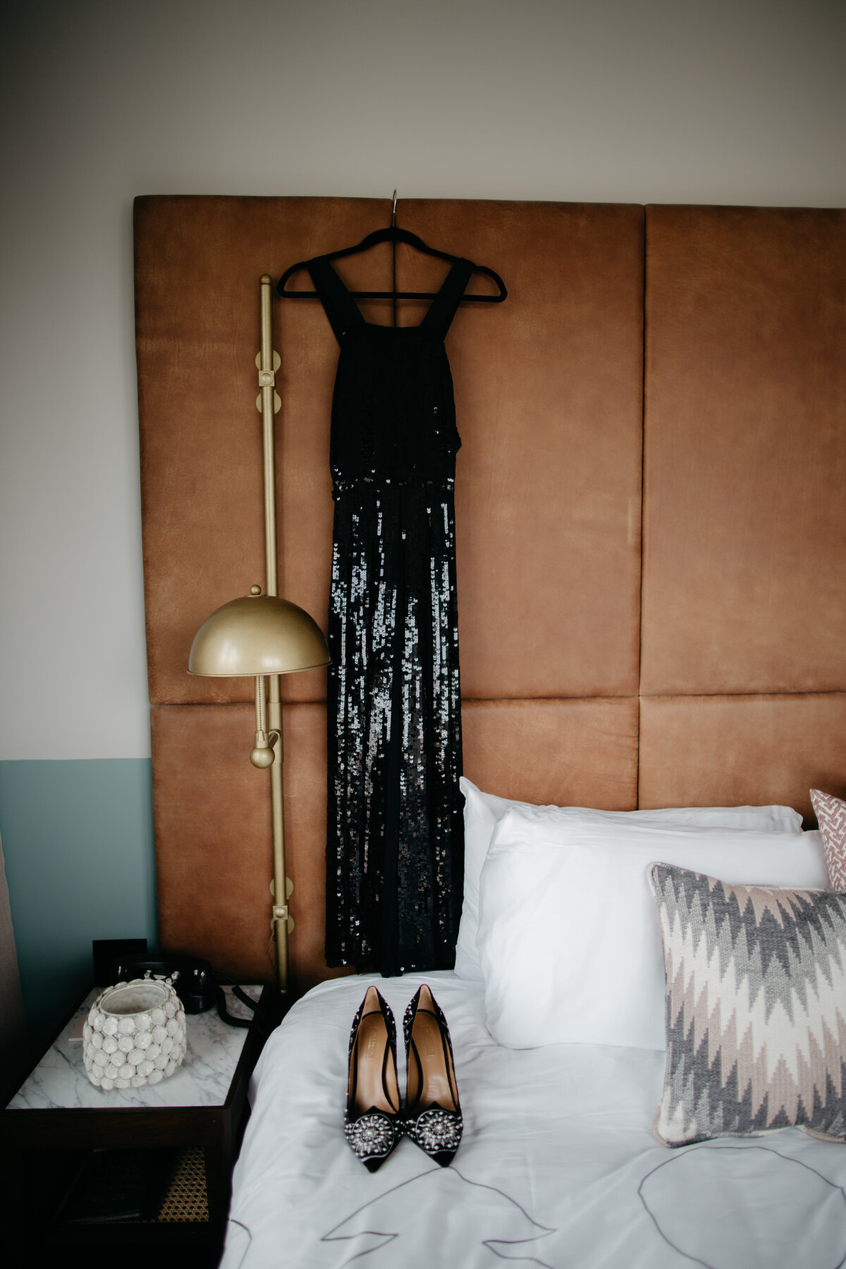 Black sequin dress hanging from leather headboard of bed in Chicago hotel