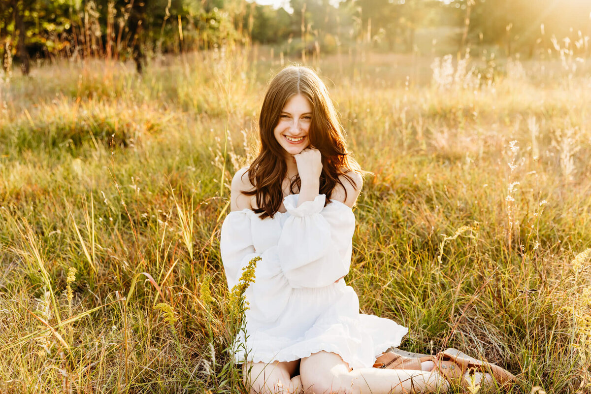 high school girl sitting in a field near Green Bay for senior portraits