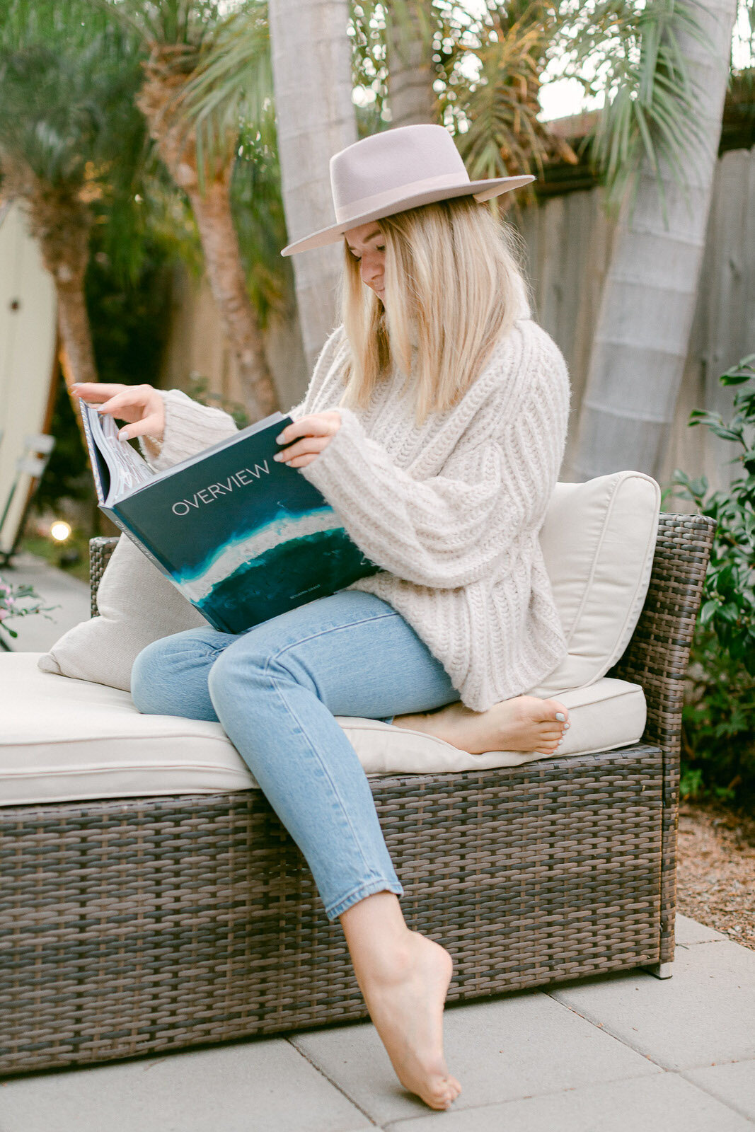 blonde girl reading surfing book on patio